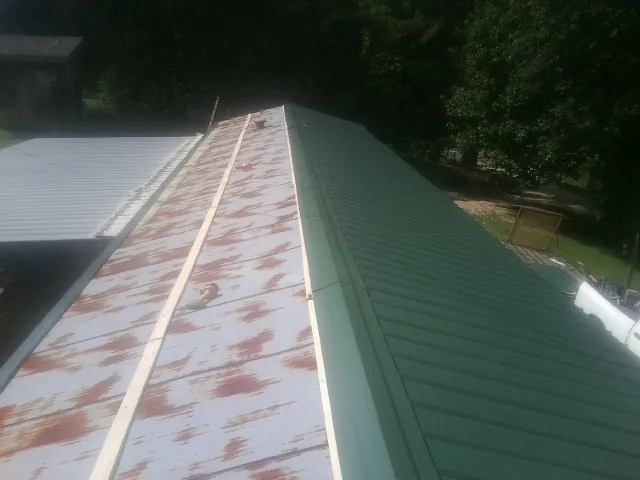 Old rusted panels beside newly installed green metal roofing — Wind Damage Roof Repair by Roofing Brothers in Tidioute