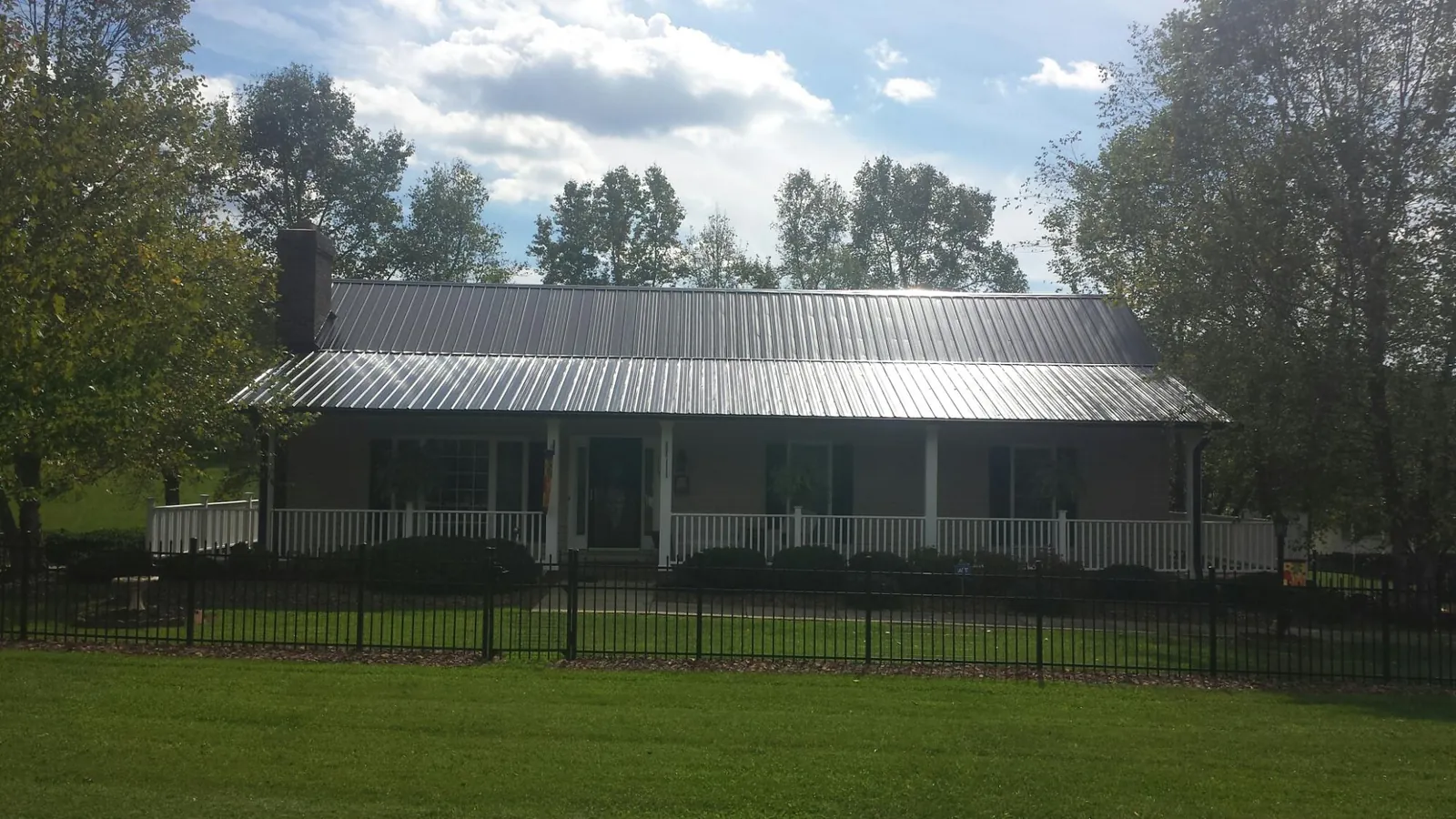 Gray metal roof on a brick ranch with a full width front porch — Gutter Guard Installation work by our crew in Tidioute