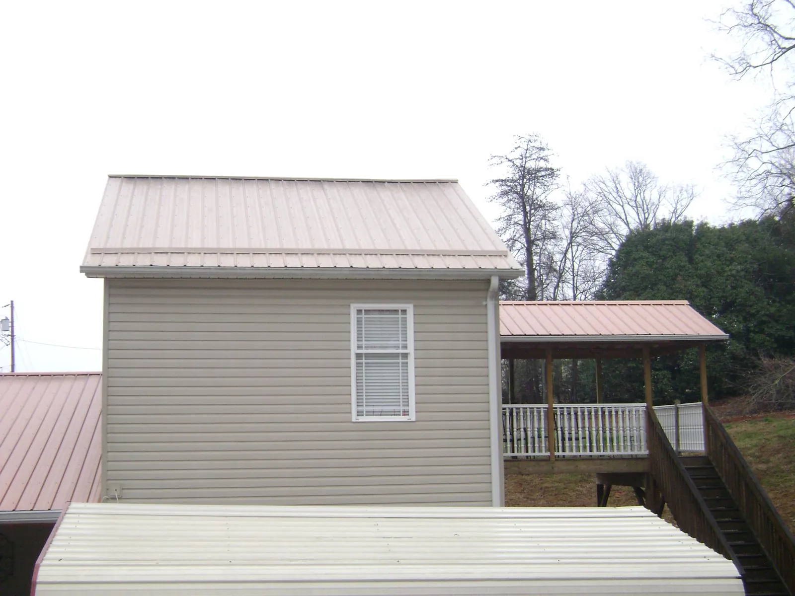 Tan metal roofs on a two story addition and attached porch, from a Roof Replacement job in Tidioute