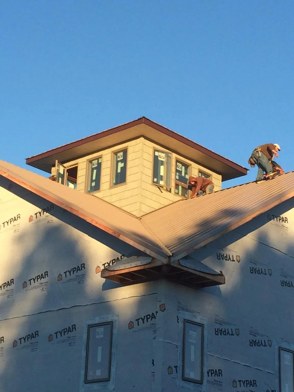 Roofers working around a rooftop cupola on a new metal roof at sunset — Roof Waterproofing in Tidioute by Roofing Brothers